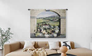 A large wall tapestry featuring a scenic Tuscan vineyard landscape under a stone archway, displayed in a modern living room setting above a beige sectional sofa.